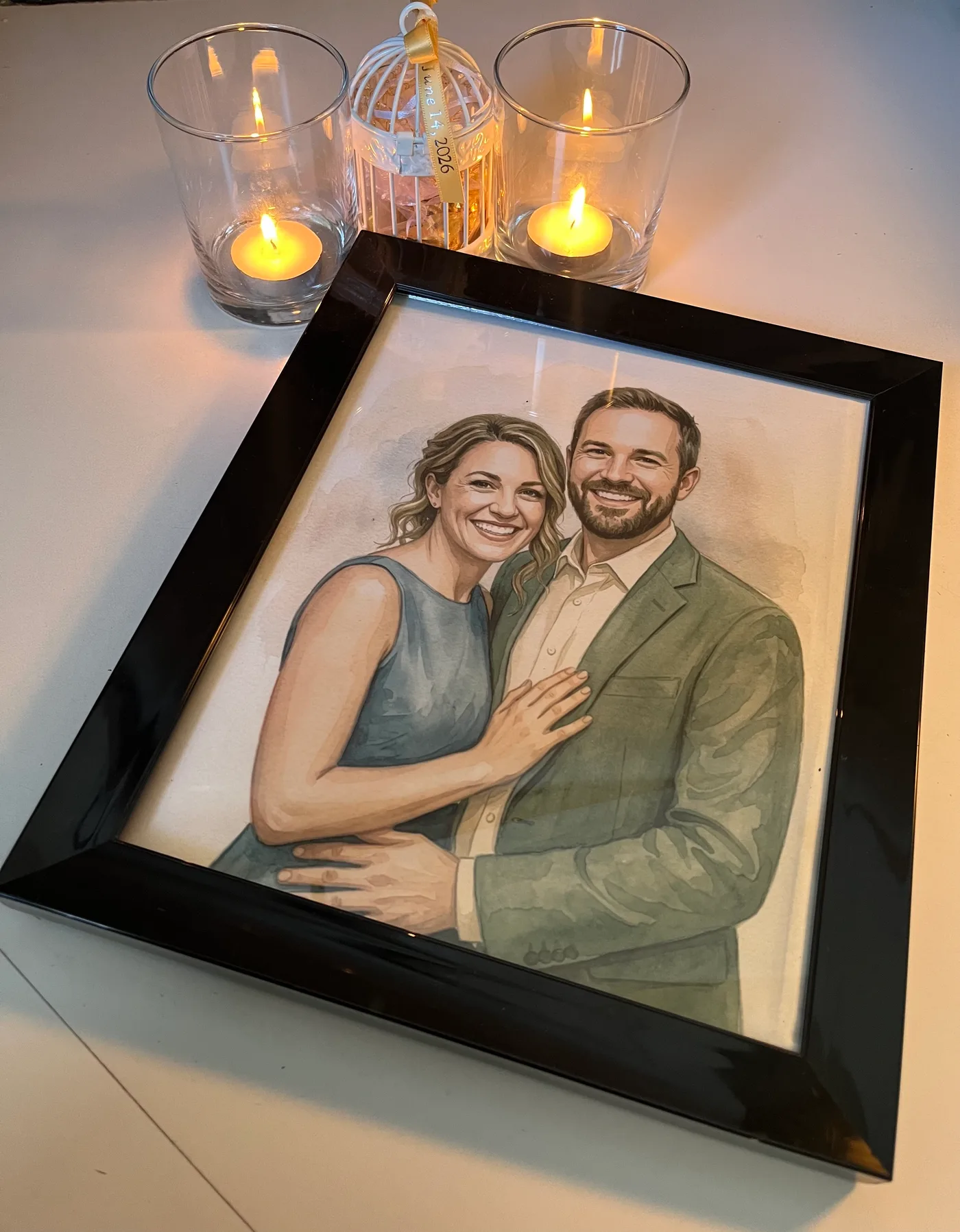 Framed watercolor couple portrait displayed with candles
